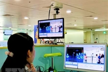 El personal del aeropuerto de Tan Son Nhat revisa la pantalla del termómetro remoto para los pasajeros internacionales que llegan a Vietnam. (Fotografía: VNA)