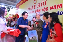 El presidente de la Asamblea Nacional de Vietnam, Vuong Dinh Hue, entrega regalos a familias con méritos revolucionarios y hogares con dificultad económica. (Fotografía: Nhan Dan)