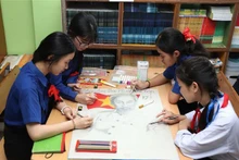 Alumnos de la escuela bilingüe laosiano-vietnamita de Nguyen Du pintan un cuadro del Tío Ho. (Fotografía: VNA)