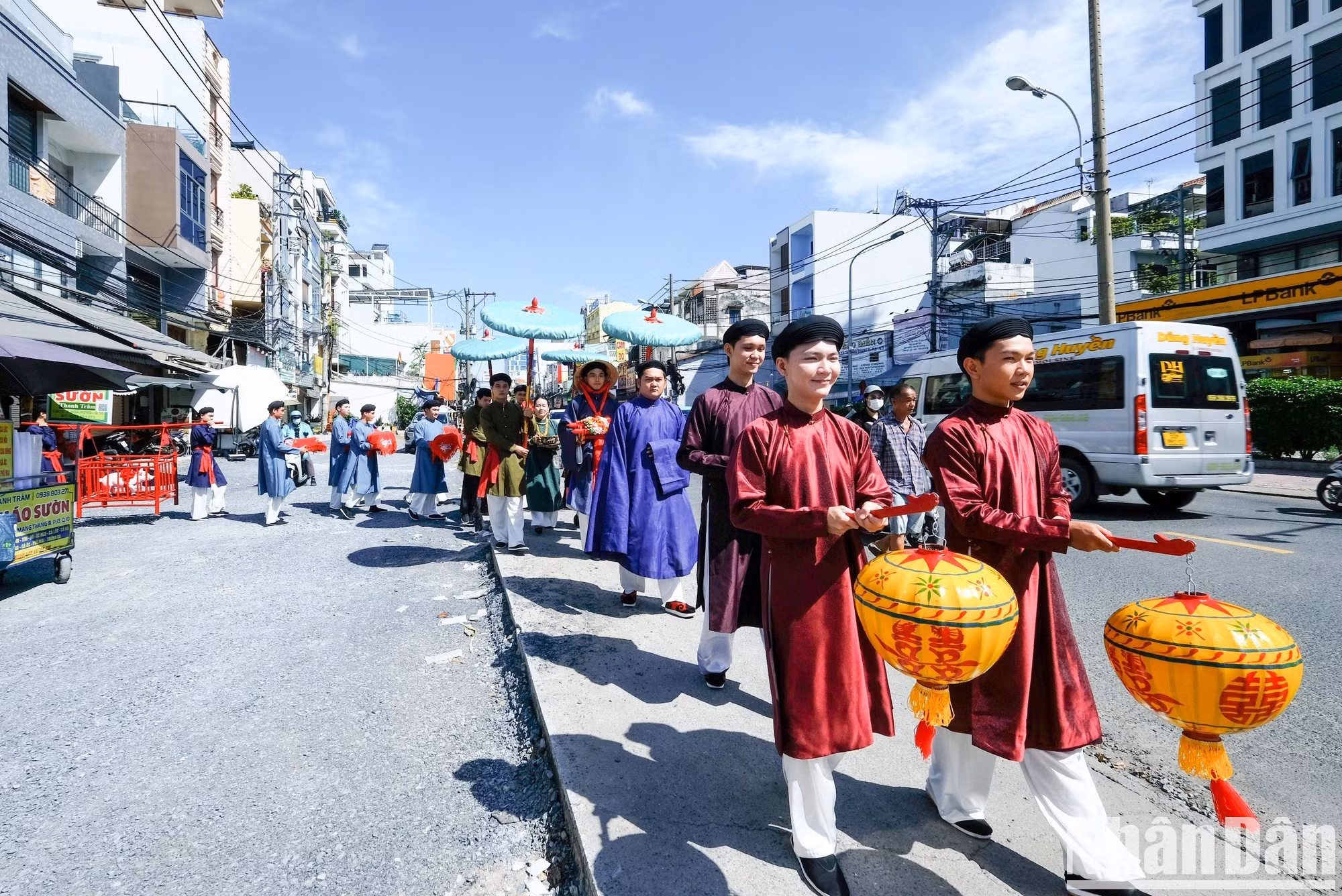Los integrantes de la comitiva nupcial visten el ao tac -un traje ceremonial tradicional vietnamita- y turbantes tradicionales y portan sombrillas ceremoniales y bandejas de ofrendas.