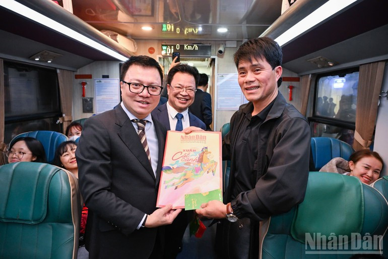 Quoc Minh entrega las ediciones especiales del Tet del diario Nhan Dan a los pasajeros.