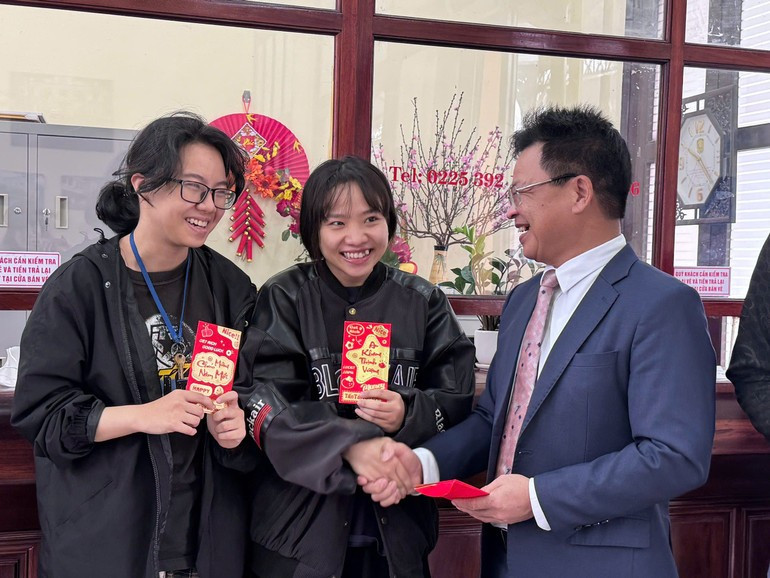 Dang Sy Manh regala un sobre rojo con dinero de suerte del Tet a los pasajeros en la estación de Hai Phong.