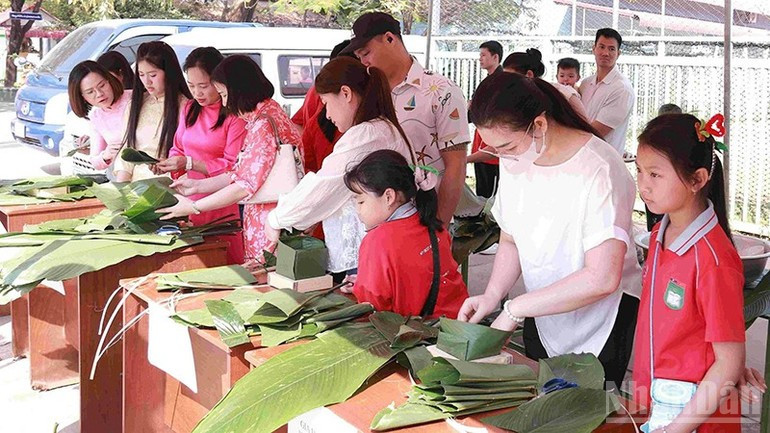 Padres y alumnos compiten en el concurso de elaboración de “banh chung” durante el evento. (Foto: Duy Toan)