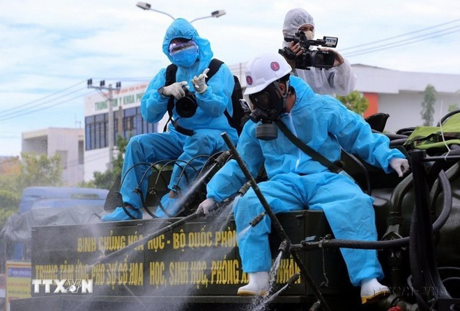 Un reportero de la VNA trabaja desde la parte trasera de un camión rociando desinfectante en zonas de alto riesgo de la pandemia del COVID-19 en Son Tra, ciudad de Da Nang. (Foto: VNA) Un reportero de la VNA trabaja desde la parte trasera de un camión rociando desinfectante en zonas de alto riesgo de la pandemia del COVID-19 en Son Tra, ciudad de Da Nang. (Foto: VNA)