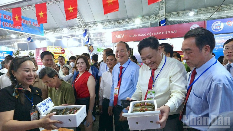 Dirigentes del Comité del Partido y del Comité Popular de la provincia de Ca Mau visitan los puestos que exhiben las especialidades de cangrejo de Ca Mau.