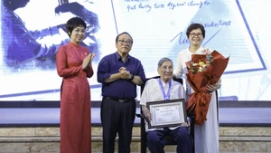 La directora general de VNA, Vu Viet Trang (primera, a la izquierda), entrega el Premio "Caballero Grillo" al compositor Pham Tuyen (sentado) durante la ceremonia. (Foto: VNA)