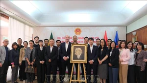 El embajador de Vietnam en Sudáfrica, Hoang Sy Cuong, y otros delegados posan para una foto conmemorativa con la familia del artista sudafricano Jan van Rooyen junto a su retrato al óleo del Presidente Ho Chi Minh. (Foto: VNA)
