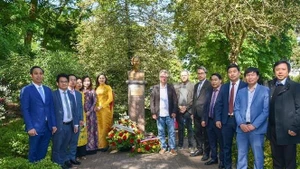 El personal de la Embajada y las agencias representativas vietnamitas en Francia toman fotografías de recuerdo en la estatua del tío Ho. (Foto: VNA)