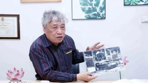 El periodista Tran Mai Huong con la foto titulada "El tanque del Ejército de Liberación entra al Palacio de Independencia al mediodía del 30 de abril de 1975". (Fotografía: VNA)