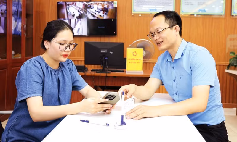 Empleado del Centro de Servicios Administrativos Públicos del distrito de Tien Phong orienta sobre la evaluación de la prestación de servicios administrativos públicos en VNeID. (Foto: baobacninhtv.vn)