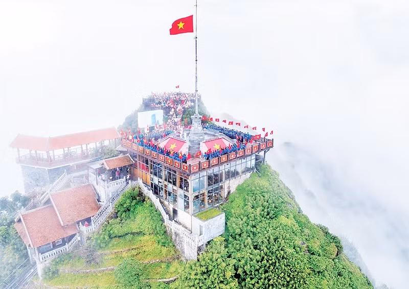 Los jóvenes realizan el saludo a la bandera y entonan el himno nacional en la cima del Fansipan.