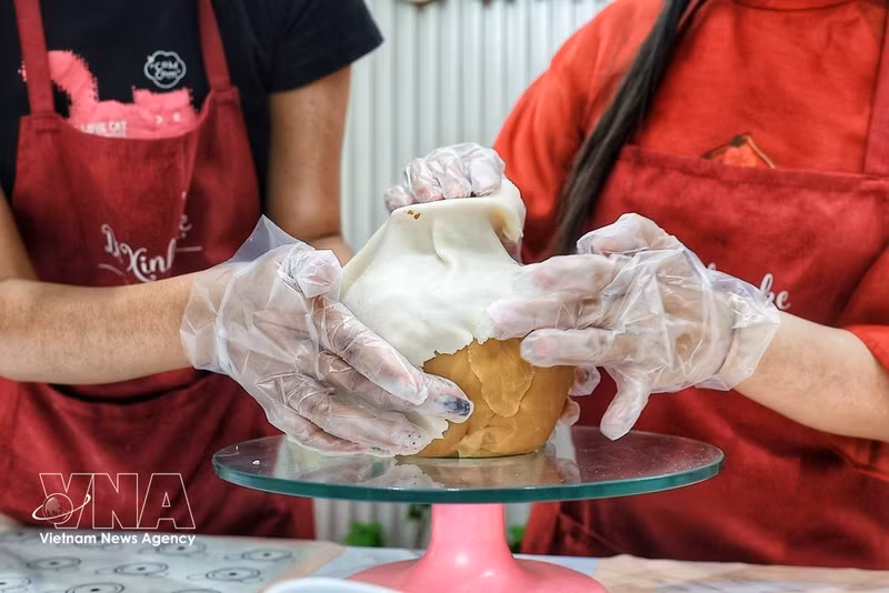 Proceso de moldeado del jarrón destinado a sostener las ramas florales elaboradas con masa para pasteles de luna. (Foto: VNA)