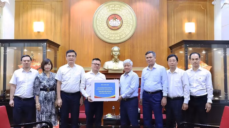 Do Van Chien, miembro del Buró Político y del Secretariado del Comité Central del Partido Comunista y presidente del Comité Central del Frente de la Patria de Vietnam, recibe el donativo de Nhan Dan. (Foto: Nhan Dan)
