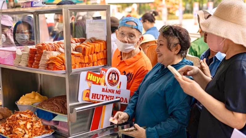 La gente compra banh mi en la tienda de Huynh Hoa. 