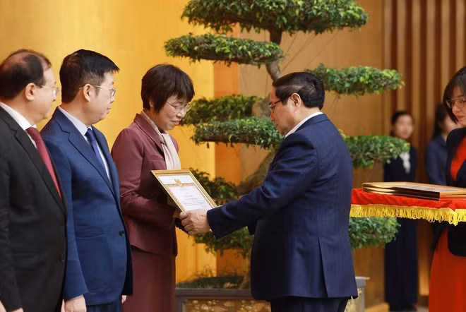 El primer ministro Pham Minh Chinh entrega certificado de reconocimiento del Comité del Partido del Gobierno a la directora general de la Agencia Vietnamita de Noticias, Vu Viet Trang. (Foto: VNA)