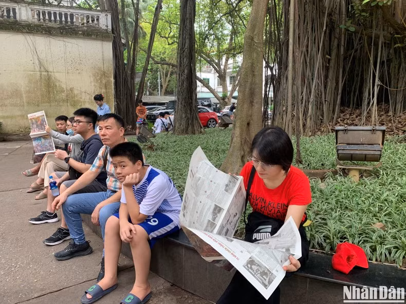 Los lectores leen el periódico Nhan Dan bajo el baniano en su sede, en el número 71 de la calle Hang Trong, en el distrito de Hoan Kiem, Hanói.