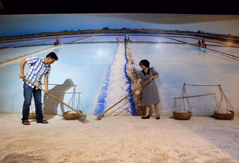 Los turistas desempeñan el papel de productores de sal en los campos de sal del Museo de Salsa de Pescado Lang Chai Xua.
