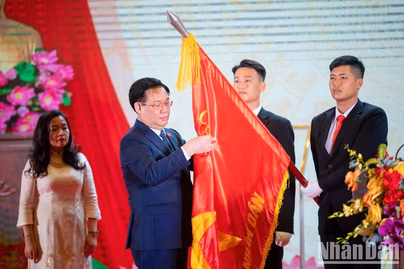 Dinh Hue coloca la Orden de Trabajo de primera clase en la bandera tradicional del periódico Dai bieu nhan dan.