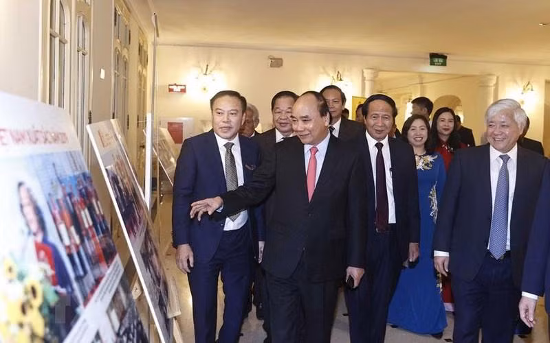 El presidente Nguyen Xuan Phuc y otros delegados visitan una exposición de fotos al margen del evento. (Foto: VNA)