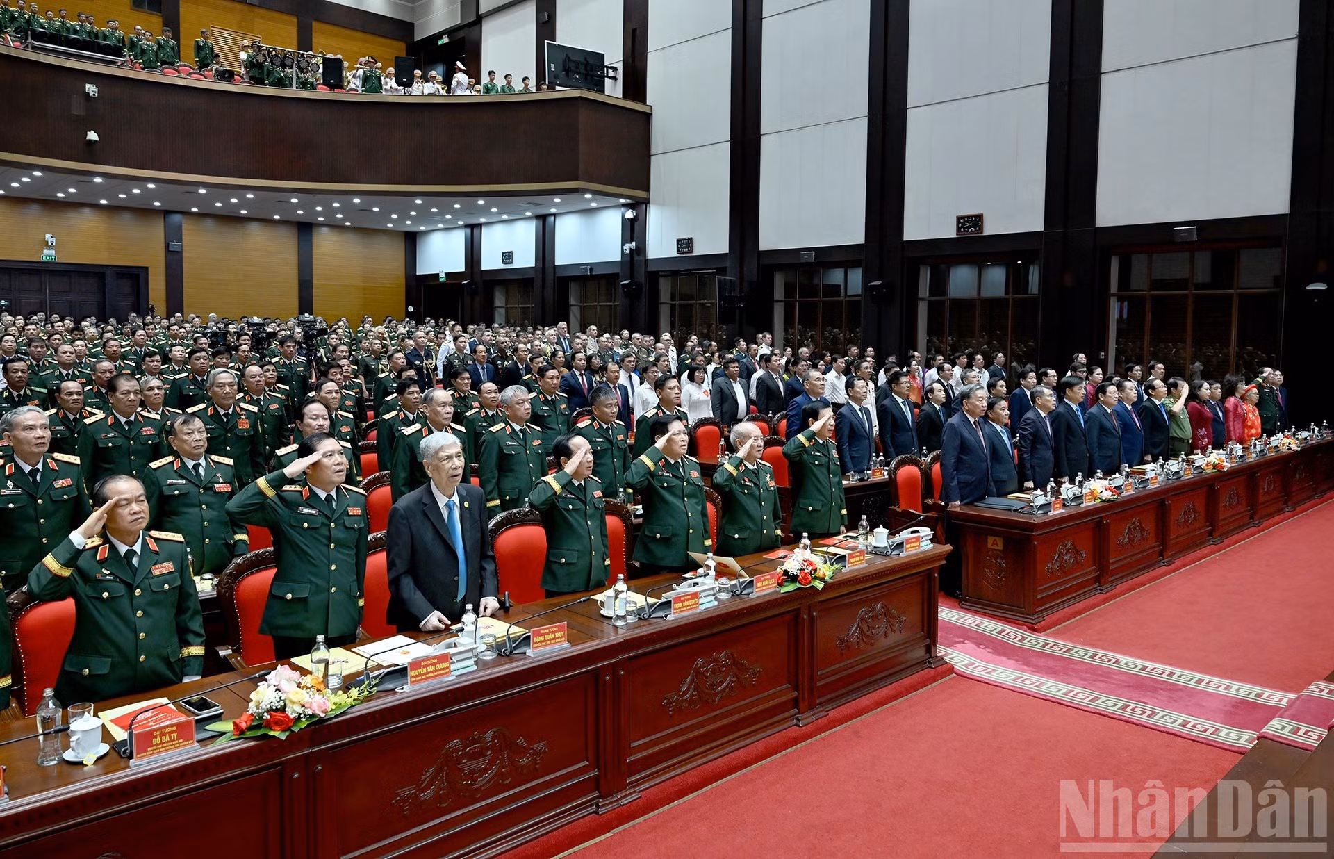 Dirigentes y exdirigentes del Partido y del Estado, junto con otros delegados, realizan el acto de saludo a la bandera.