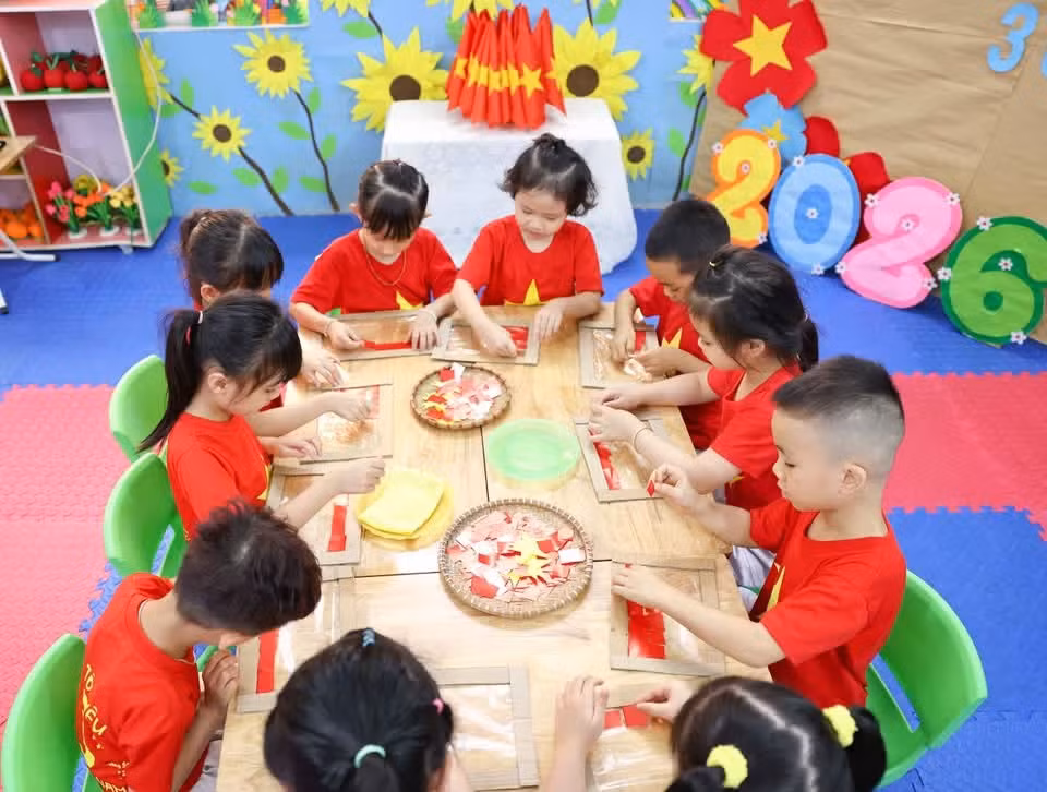 Los niños de preescolar recortan y pegan con cuidado y dedicación para formar una bandera nacional brillante.