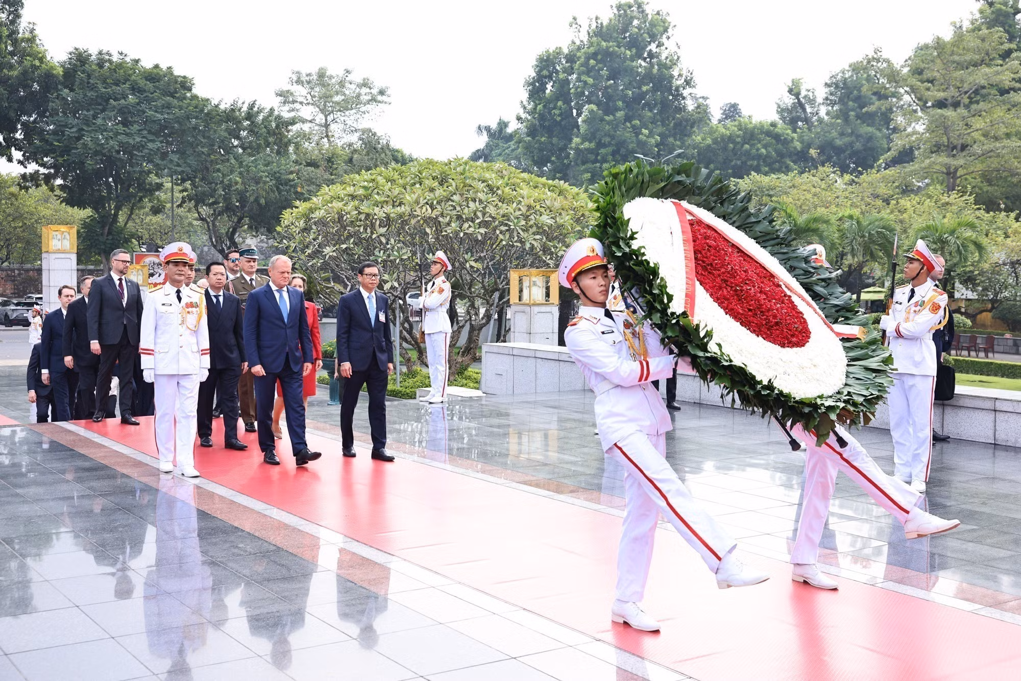 El primer ministro de Polonia, Donald Tusk, encabeza una ceremonia de colocación de ofrenda floral en el Monumento a los héroes y mártires de guerra en la calle de Bac Son, en Hanói.