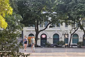 Turistas extranjeros pasean bajo los árboles frondosos a orillas del lago Hoan Kiem, disfrutando del ambiente fresco de la capital. (Foto: VNA)