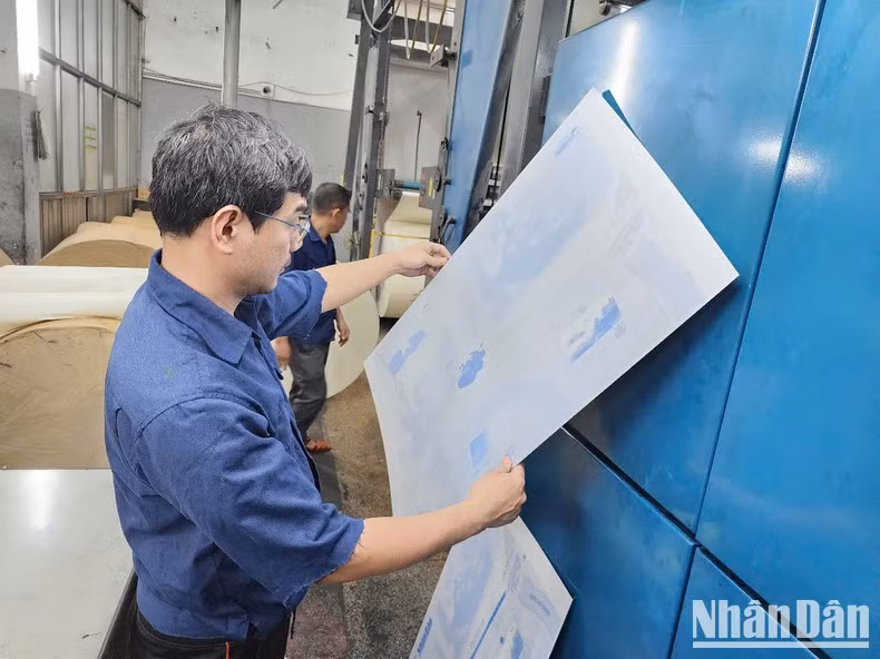 Trabajadores de la imprenta del periódico Nhan Dan instalan planchas metálicas para proceder a la impresión.