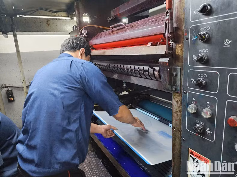 Trabajadores de la imprenta del periódico Nhan Dan instalan planchas metálicas para proceder a la impresión.