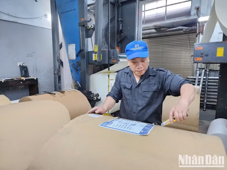 Trabajadores de la imprenta del periódico Nhan Dan procesan el papel de impresión.