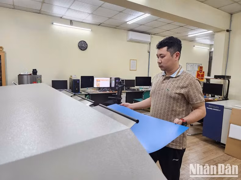 Trabajadores de la imprenta del periódico Nhan Dan preparan planchas metálicas de impresión.