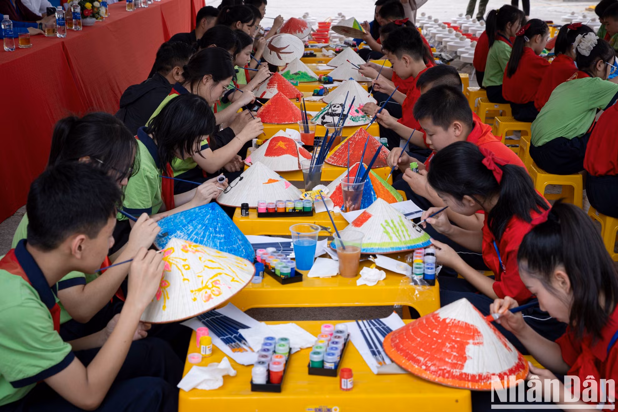Los estudiantes participan en la actividad de pintar sombreros cónicos.