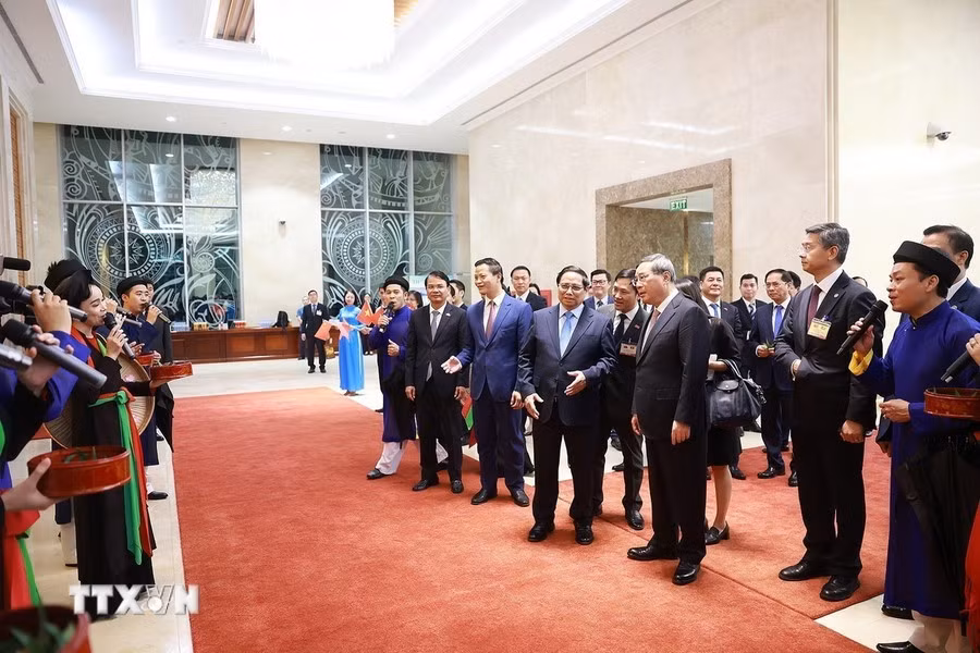 Los cantantes masculinos (Lien anh, en vietnamita), y femeninos (Lien chi) que interpretan el canto popular de Quan Ho (canto de dúo de amo) de la norteña provincia de Bac Ninh saludan al primer ministro chino, Li Qiang.