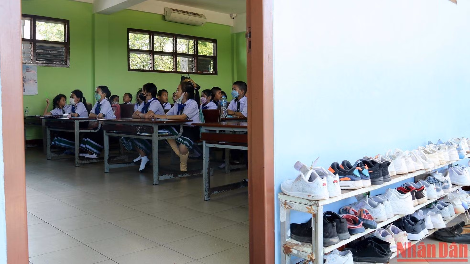 Los zapatos están ordenados en el estante fuera del salón de clases.