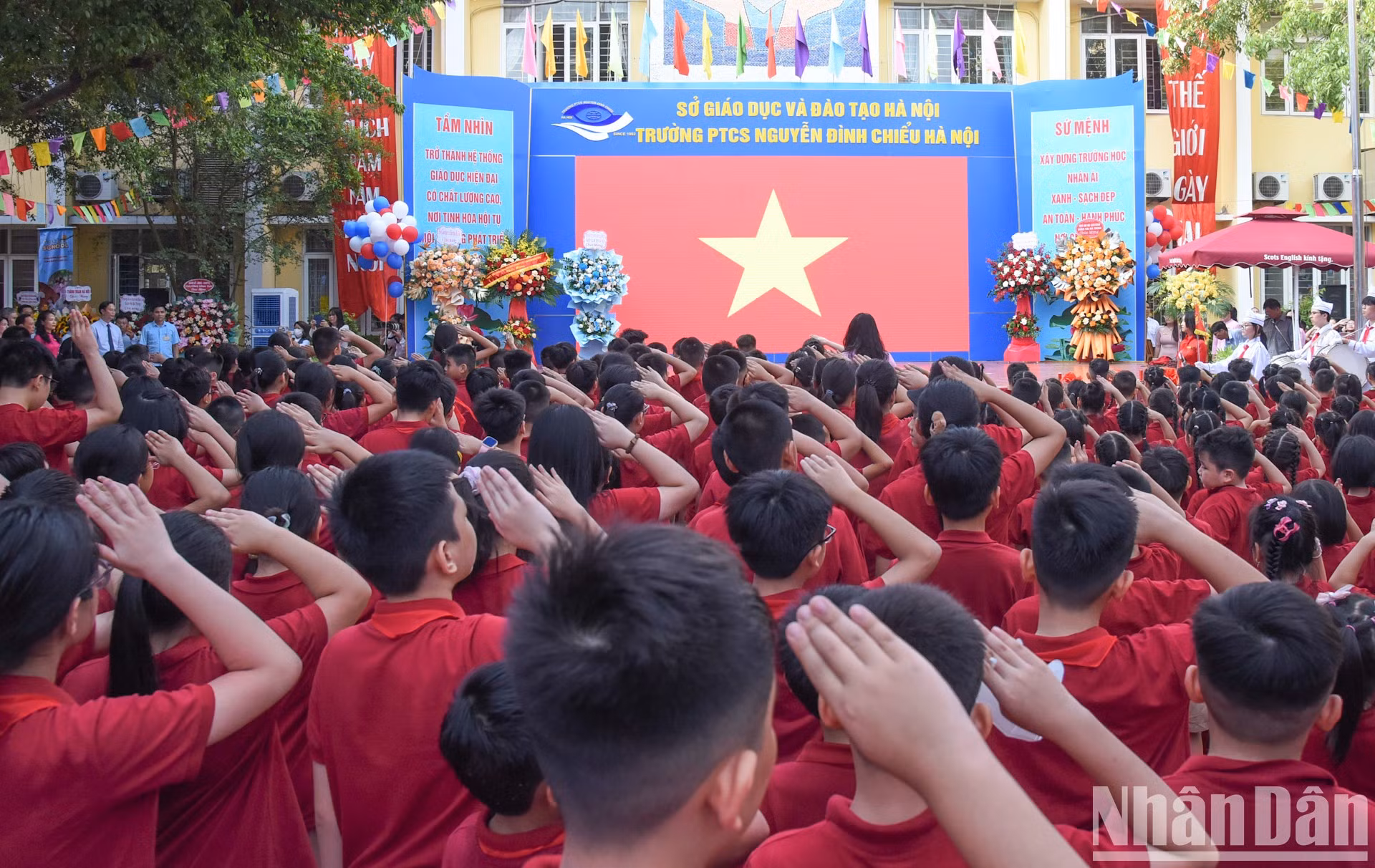 Delegados, docentes y estudiantes saludan a la bandera nacional.