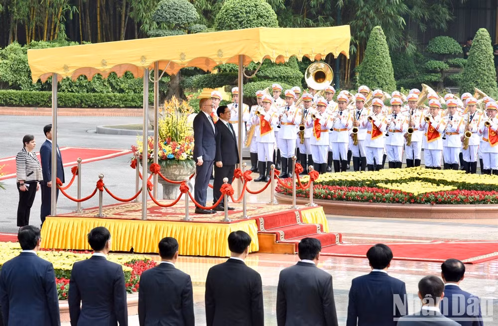 Los dos premieres se paran el podio de honor mientras se entonan los himnos de los dos países.