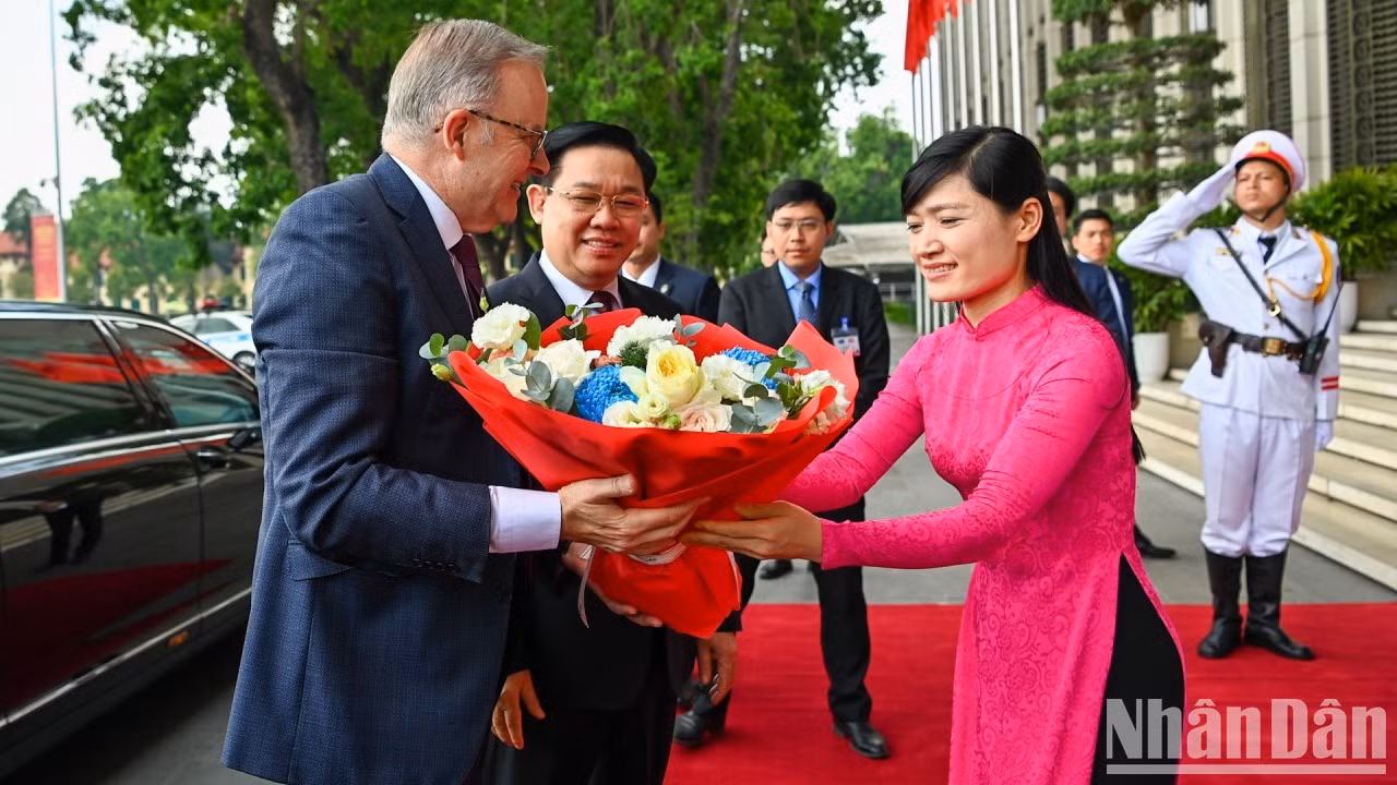 Miembro de la Oficina de la Asamblea Nacional de Vietnam entrega flores para dar la bienvenida al primer ministro australiano, Anthony Albanese.
