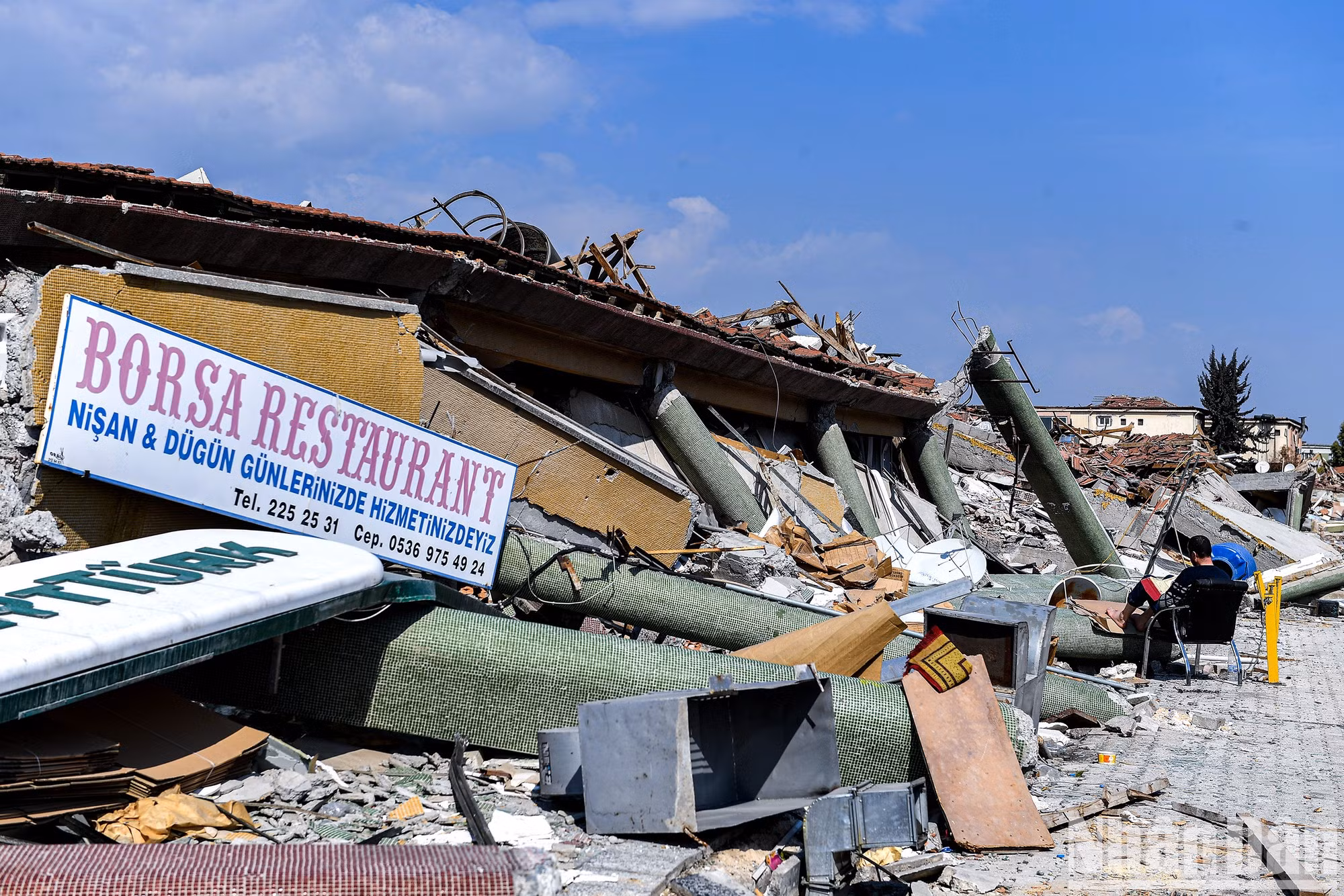 Tras el fatídico terremoto, hay personas que consiguen recuperar la calma, leyendo libros junto a edificios derrumbados.