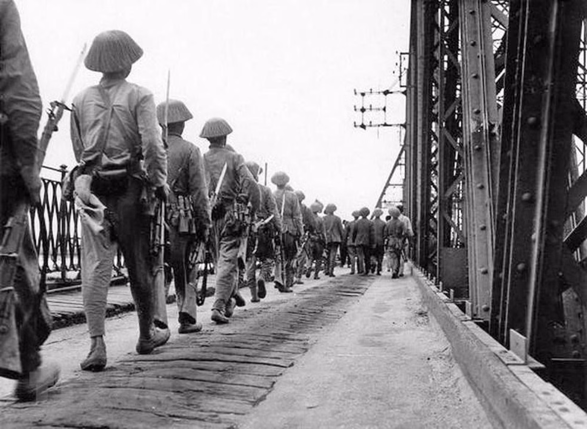 Las tropas vietnamitas marchan imponentes por el puente de Long Bien hacia la capital nacional, mientras desde el otro lado se retiran los franceses, la tarde del 9 de octubre de 1954.