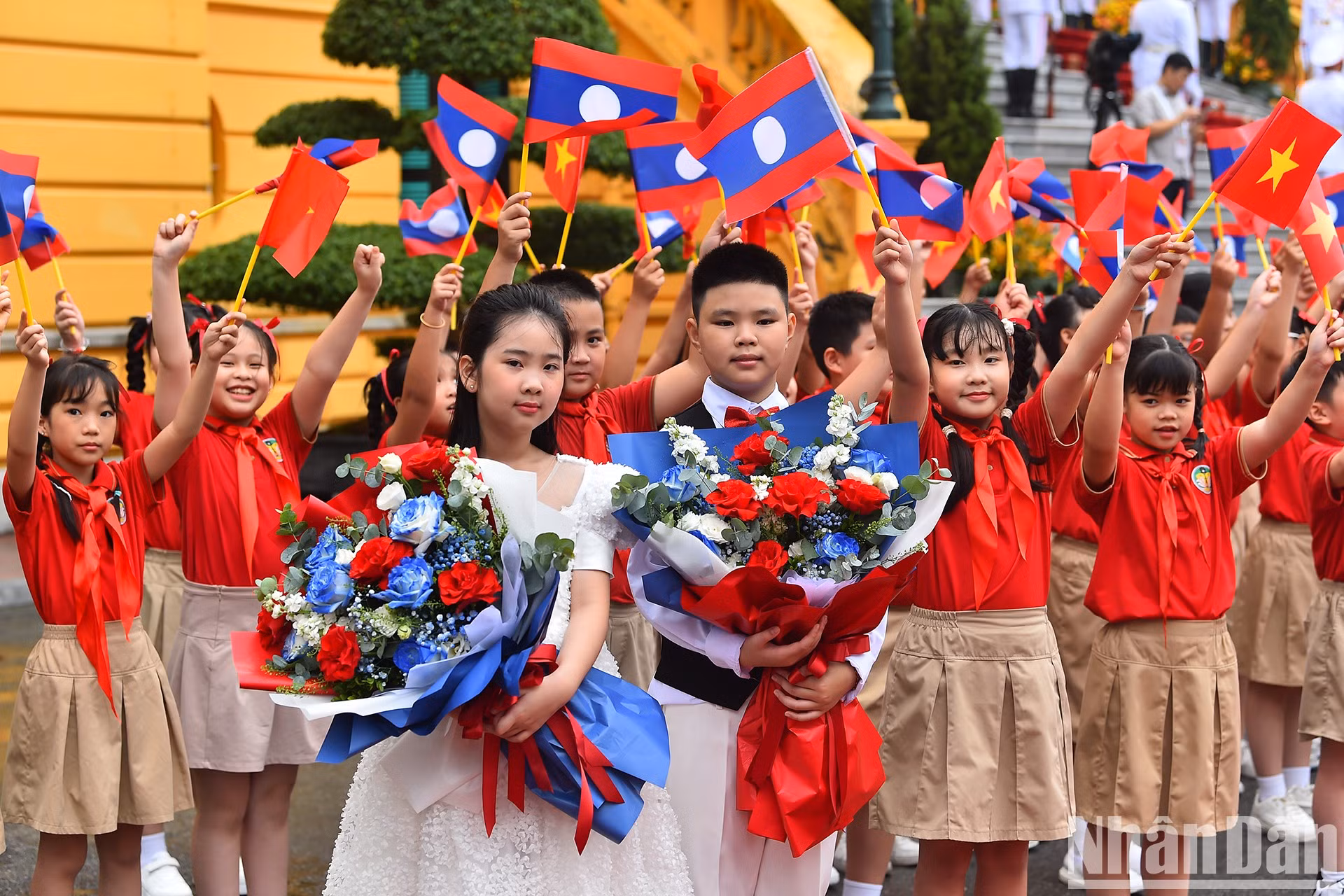 Niños capitalinos dan la bienvenida al máximo dirigente laosiano y su cónyuge, acompañados de una delegación de alto nivel de ese país, en su visita a Vietnam.