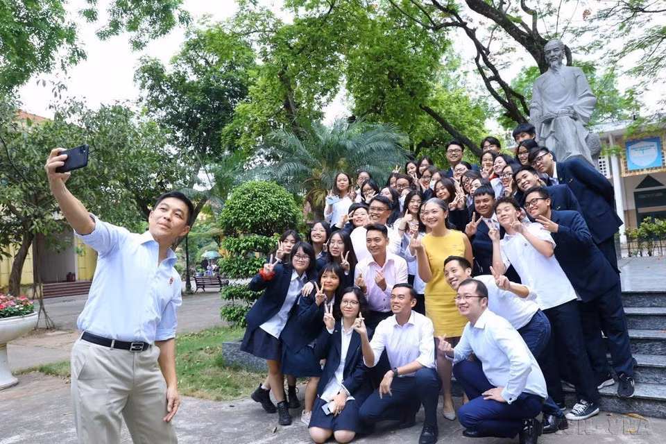 El presidente del Parlamento de Singapur, Tan Chuan-Jin, se toma el 19 de mayo de 2022 una selfie con estudiantes frente a la estatua del maestro Chu Van An en el campus de la Escuela Secundaria de Chu Van An.
