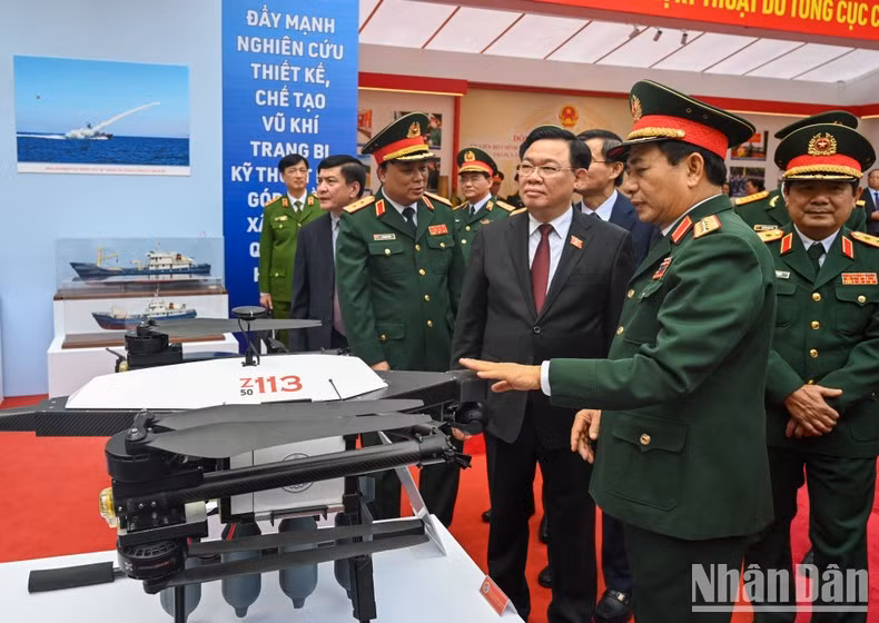 Dinh Hue y delegados visitan la exhibición de armamento.