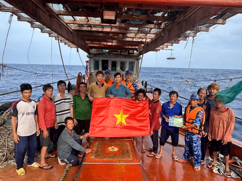 Las fuerzas de seguridad marítima de Ciudad Ho Chi Minh entregan la bandera nacional y difunden medidas preventivas contra la pesca INDNR a los marineros. (Foto: VNA)