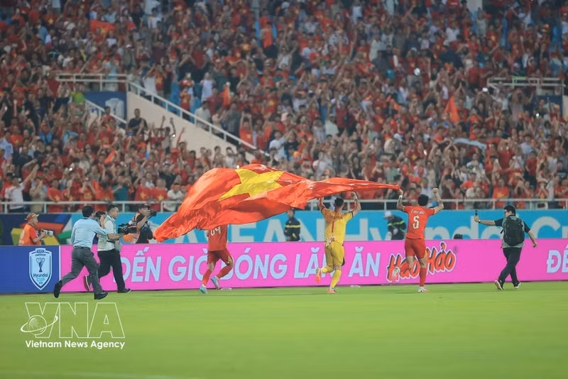 El guardameta Le Giang Patrik y sus compañeros levantan la bandera nacional de Vietnam y dan la vuelta al campo tras el final del partido. (Foto: VNA)