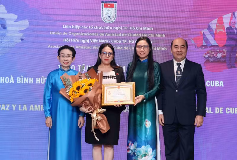 La cónsul general de Cuba en Ciudad Ho Chi Minh, Ariadne Feo Labrada (segunda a la izquierda), recibe la insignia “Por la paz y la amistad entre los pueblo” de la VUFO en el evento. (Foto: VNA)