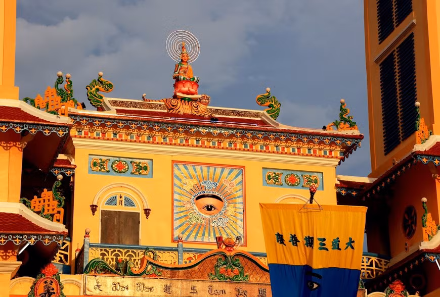 Una estatua de Buda sobre un loto y una escultura del Ojo Divino frente a la Santa Sede de Tay Ninh. Una estatua de Buda sobre un loto y una escultura del Ojo Divino frente a la Santa Sede de Tay Ninh.