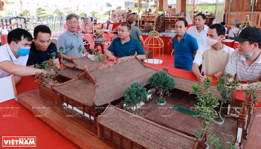 Visitantes disfrutan del modelo del templo comunal de madera más pequeño de Vietnam. (Fuente: VNA)