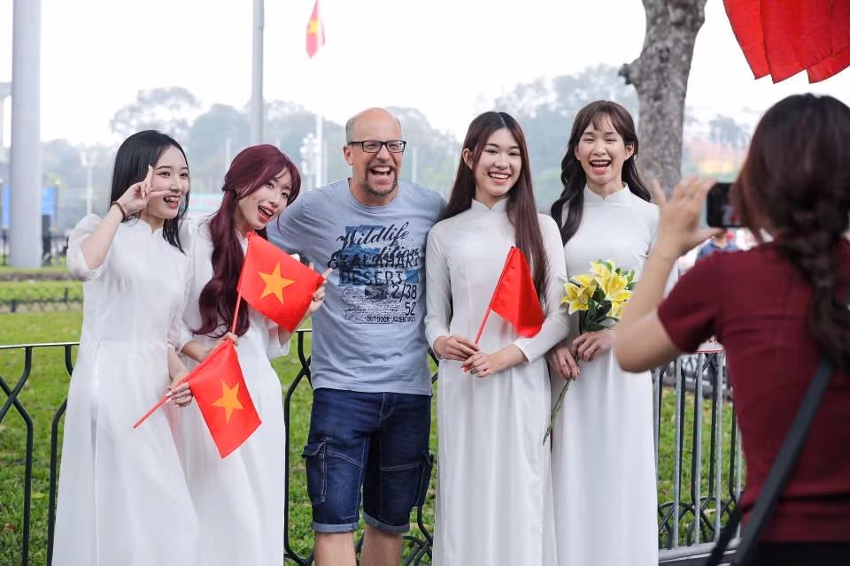 Visitantes extranjeros disfrutan tomándose fotos con la bandera vietnamita. (Foto: VNA)