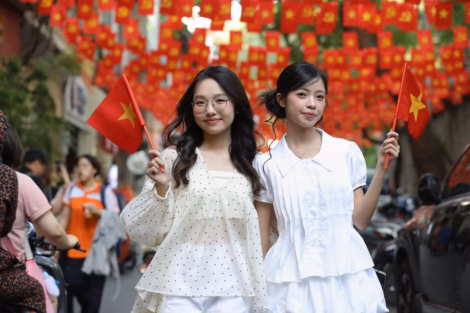 La calle de Au Trieu, con banderas rojas con estrella amarilla ondeando, atrae a muchos jóvenes a tomarse fotos para unirse al ambiente de celebración por el 30 de abril. (Foto: VNA)