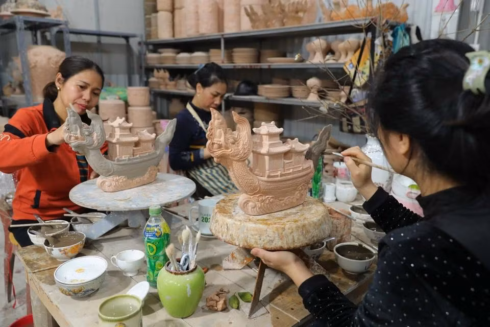 Aplicando esmalte sobre la cerámica "Ngu long khanh hoi" en el taller del artesano Nguyen Trong Nghia en el pueblo de cerámica Bat Trang.